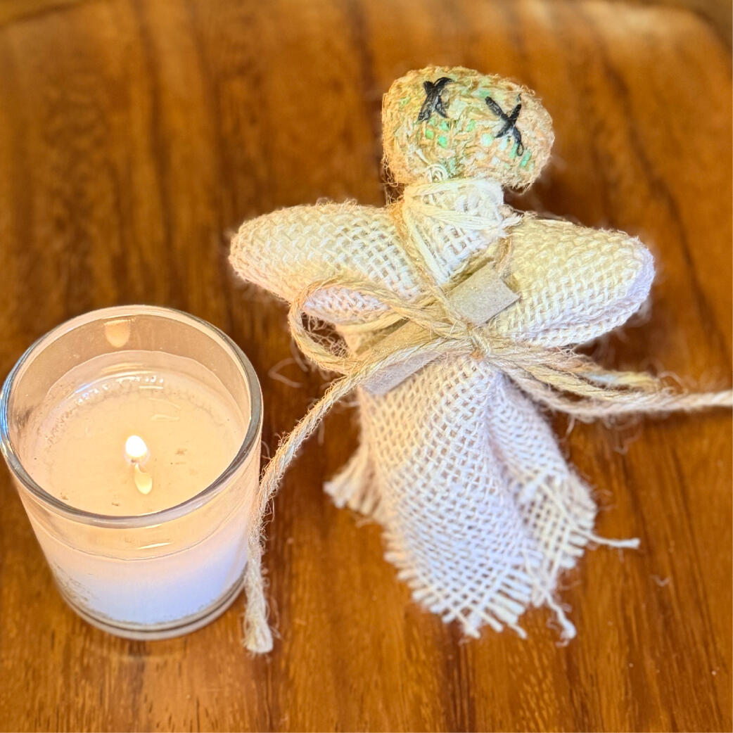 Single burlap Cinderwitch beside a lit candle, handmade wish-burning ritual figure by WMFrewolfe
