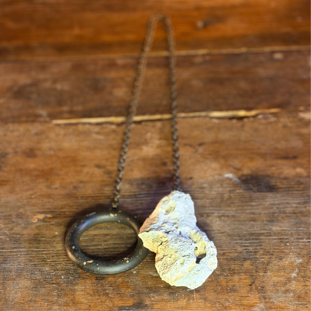 Natural water-holed hagstone beside its wooden ring, handmade seeing-stone pendulum, Hagulum by WMFrewolfe