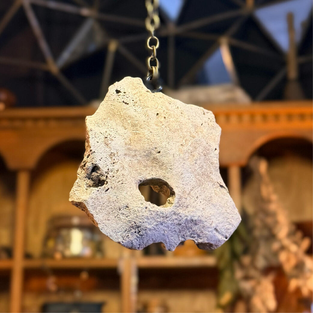 Hagstone hung on a long chain with the natural hole catching light, seeing and warding pendulum, Hagulum by WMFrewolfe